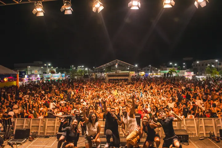 Banda no palco com o público lotando a praça à noite